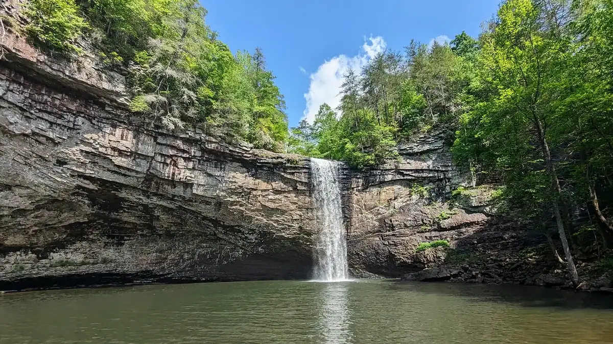 Hiker at the base of 60-foot Foster Falls next to the plunge pool