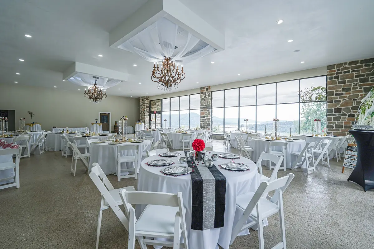 Lookout Winery event hall set with round tables and chandeliers, lake through the windows
